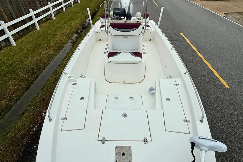 Slide: The Image of 2003 Blazer 2220 Bay boat on road, white deck, maroon seats, fenced grass area. - 14