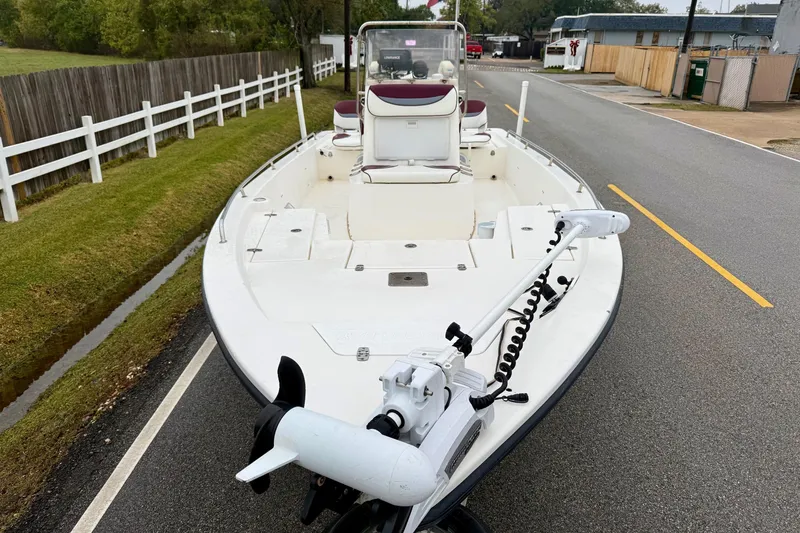Slide: The Image of 2003 Blazer 2220 Bay boat on road, featuring trolling motor and white fencing. - 6
