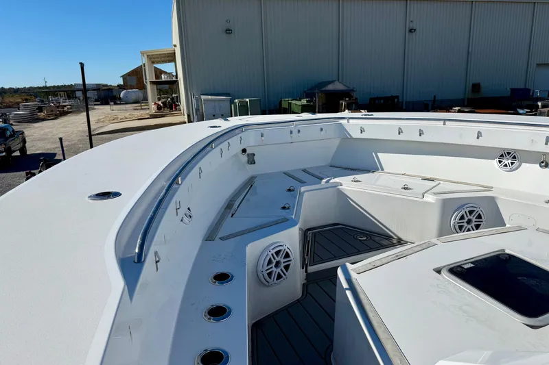Slide: The Image of 2021 Gulf Crosser 44 boat deck with seating and storage, docked near industrial buildings. - 8