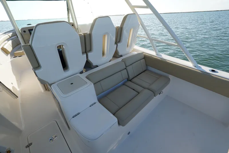 Slide: The Image of 2016 Pursuit ST 310 Sport boat interior with cushioned seating and ocean view. - 11