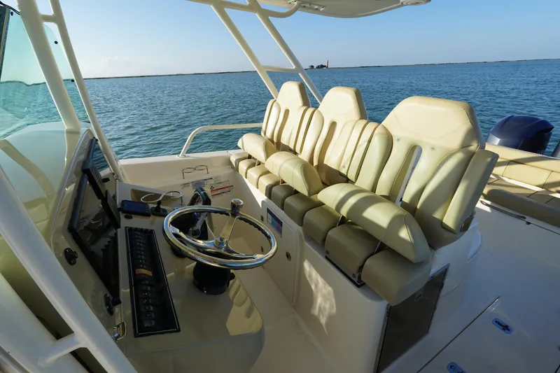 Slide: The Image of 2016 Pursuit ST 310 Sport boat interior with helm and seating, on calm water. - 17