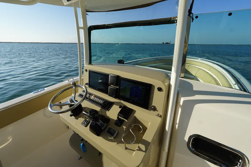 Slide: The Image of 2016 Pursuit ST 310 Sport boat dashboard with steering wheel and navigation screens on open water. - 19