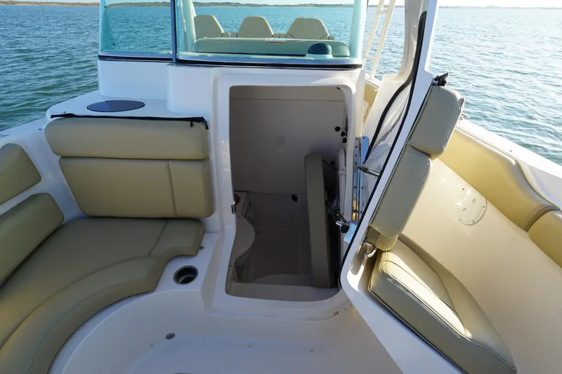 Slide: The Image of 2016 Pursuit ST 310 Sport boat interior with open cabin door, beige seating, and ocean view. - 25