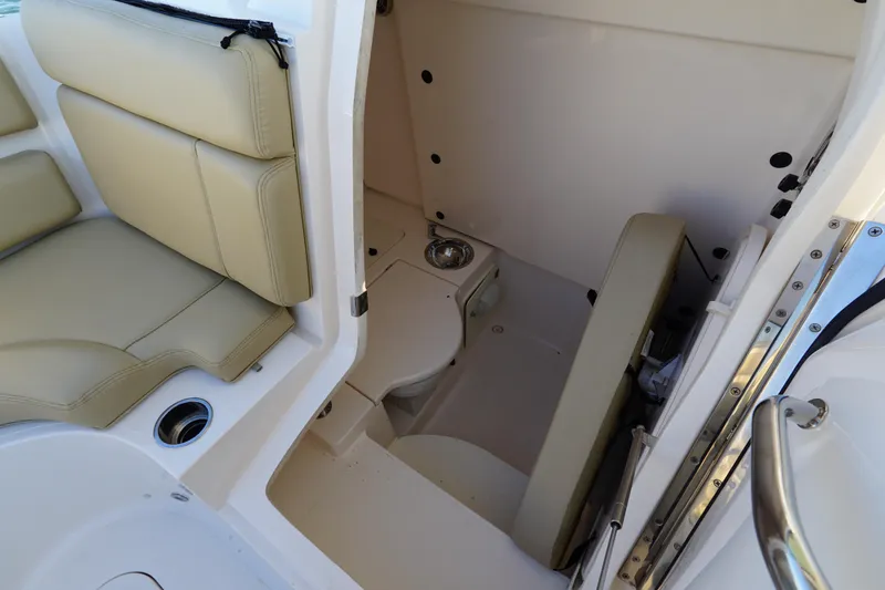 Slide: The Image of 2016 Pursuit ST 310 Sport boat interior with beige seating and compact restroom. - 26
