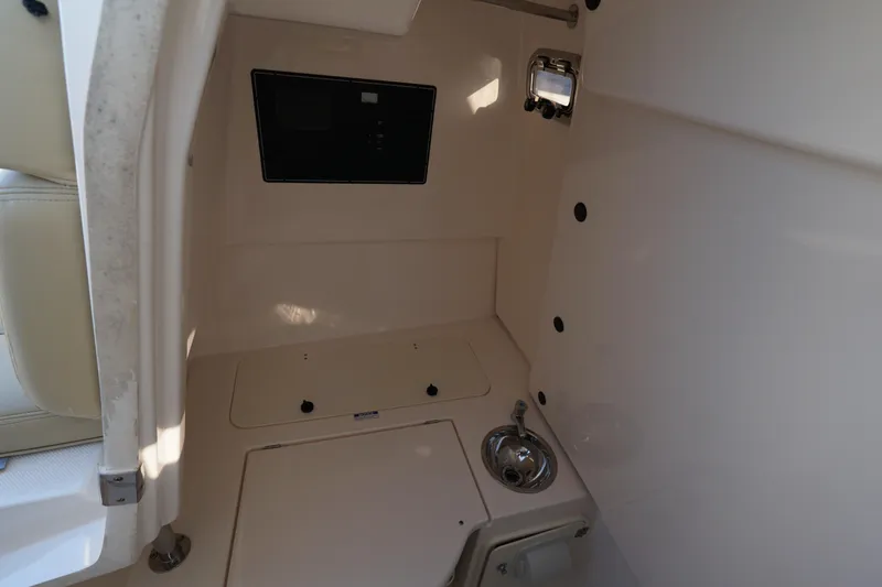 Slide: The Image of Interior of 2016 Pursuit ST 310 Sport boat, featuring a compact sink and storage area. - 27
