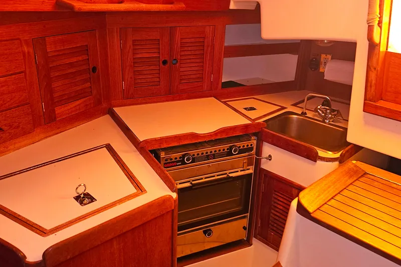 Slide: The Image of 1994 Tartan 3100 yacht kitchen with wooden cabinets, stove, and sink. - 11