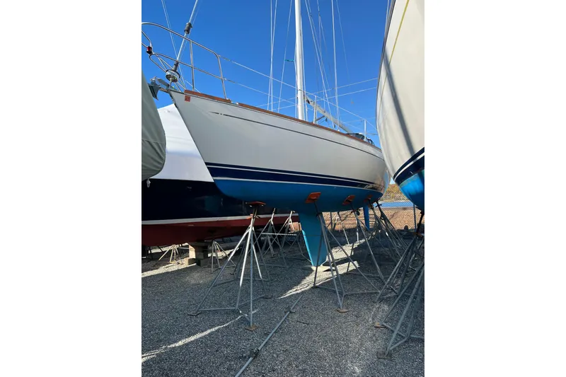 Slide: The Image of 1994 Tartan 3100 sailboat on stands, displayed outdoors under clear blue sky. - 3