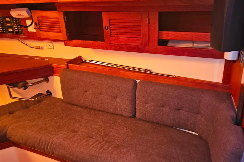 Slide: The Image of Cozy interior of a 1994 Tartan 3100 sailboat with wooden cabinets and cushioned seating. - 7