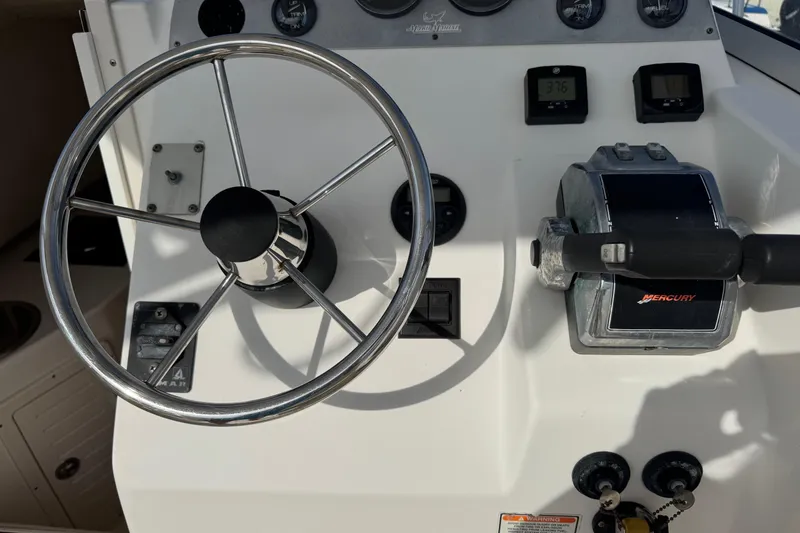 Slide: The Image of Control panel of a 2006 Mako 253 Walk Around boat with steering wheel and Mercury throttle. - 10