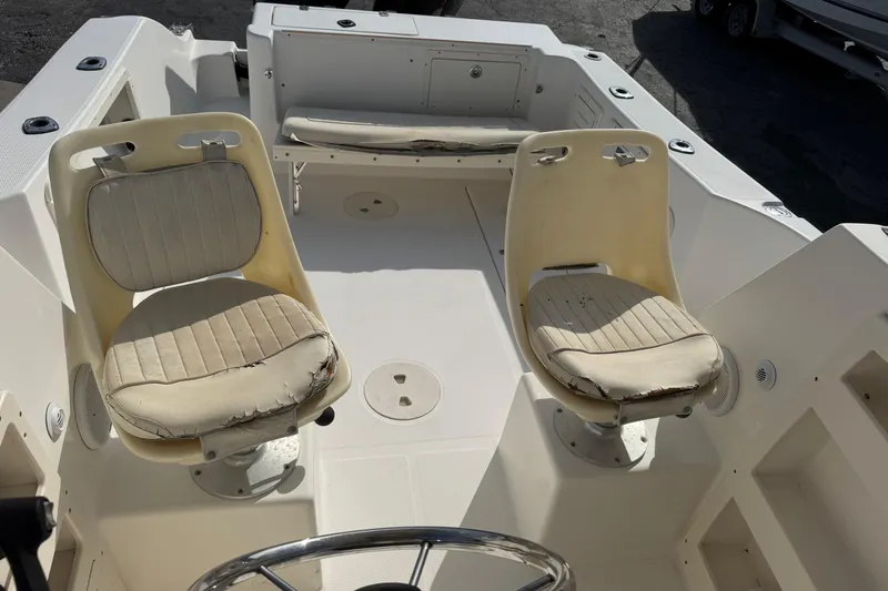Slide: The Image of 2006 Mako 253 Walk Around boat interior with two worn seats. - 16