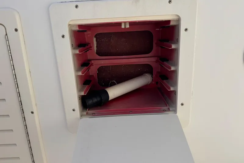 Slide: The Image of Open storage compartment on 2006 Mako 253 Walk Around boat, featuring a white and red interior. - 23