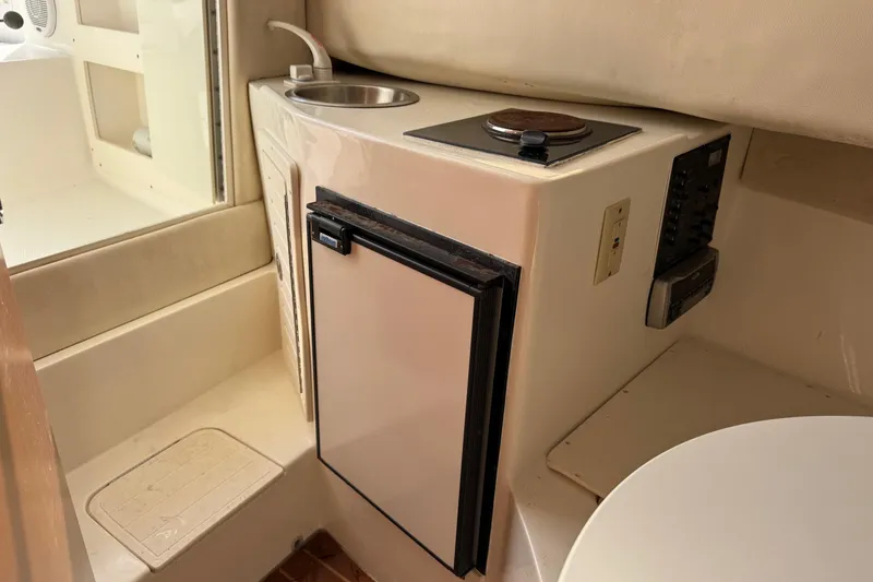 Slide: The Image of 2006 Mako 253 Walk Around boat interior with kitchenette, sink, and compact fridge. - 25