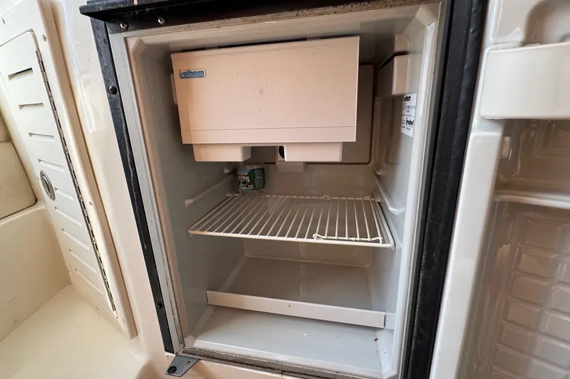 Slide: The Image of Open fridge inside 2006 Mako 253 Walk Around boat, showing interior shelves. - 27