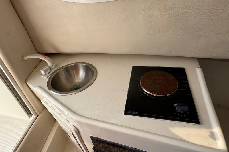 Slide: The Image of Compact kitchenette in 2006 Mako 253 Walk Around boat with sink and stove. - 28