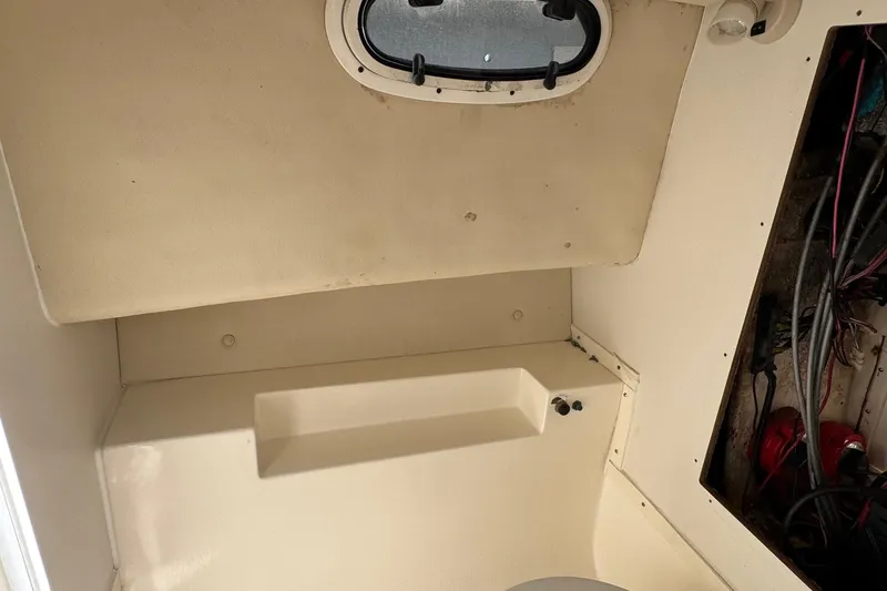 Slide: The Image of Interior cabin of 2006 Mako 253 Walk Around boat, featuring a small window and storage area. - 32