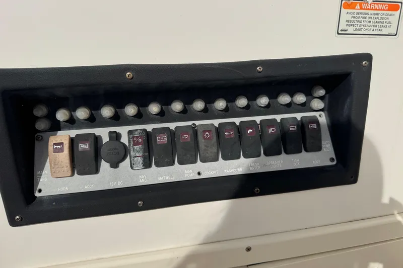 Slide: The Image of Control panel of a 2006 Mako 253 Walk Around boat with labeled switches. - 9