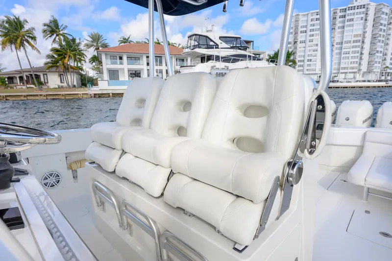 Slide: The Image of 2017 SeaVee 390Z boat with white cushioned seats, dockside view, palm trees, and buildings. - 5