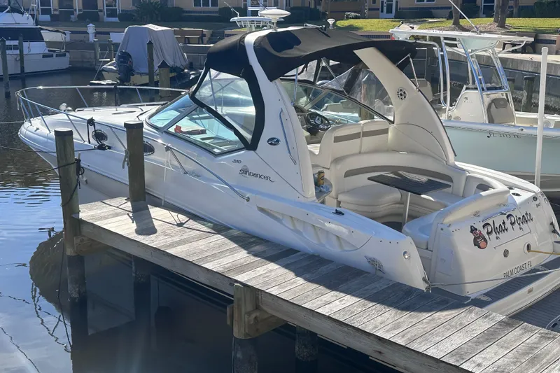 The Image of 2004 Sea Ray 320 Sundancer yacht docked near waterfront homes. - 1