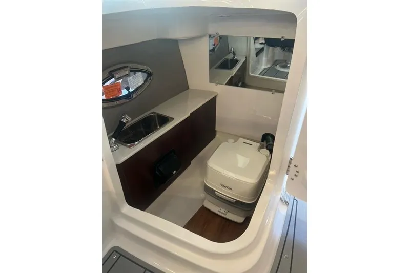 Slide: The Image of Interior of 2025 Chaparral 267 SSX boat featuring compact bathroom with sink and toilet. - 16
