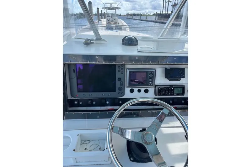 Slide: The Image of Dusky 278 boat cockpit, 2006 model, featuring steering wheel and control panel, surrounded by greenery. - 14