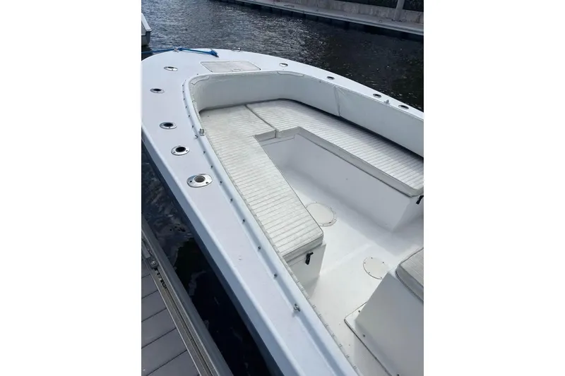 Slide: The Image of 2006 Dusky 278 boat interior with seating and storage, shaded by trees. - 27