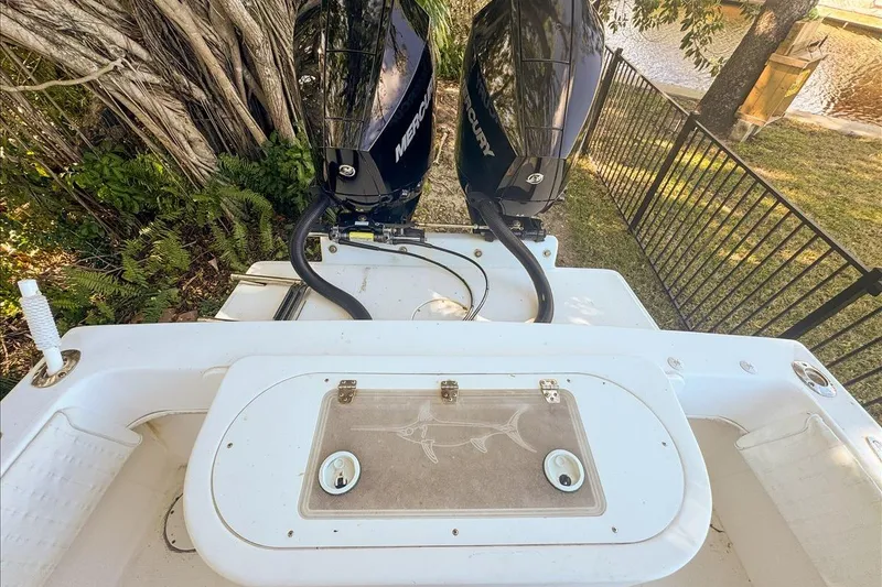 Slide: The Image of 2006 Dusky 278 boat with dual Mercury engines, docked near a fenced waterfront area. - 58