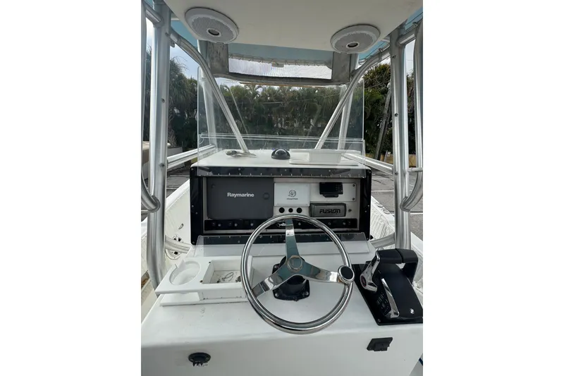 Slide: The Image of 2006 Dusky 278 boat interior with steering wheel and control panel, surrounded by greenery. - 12