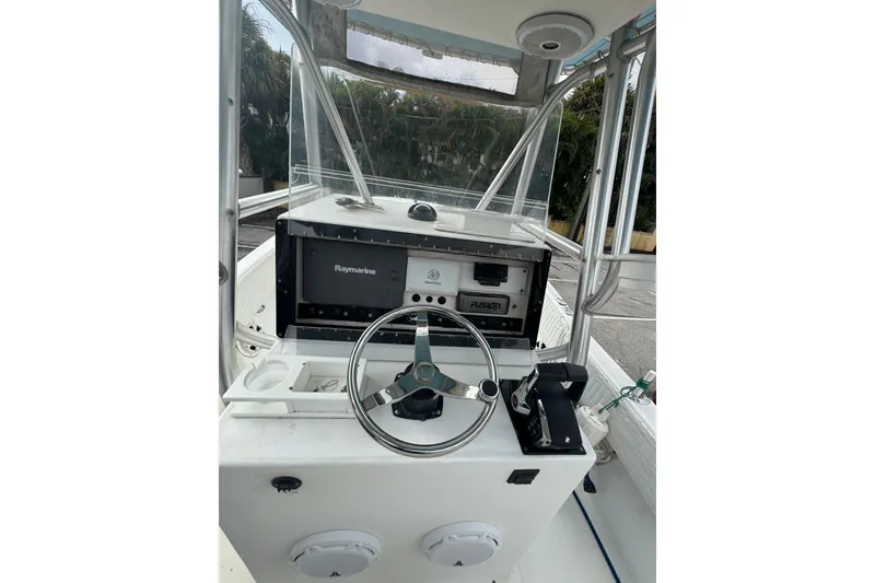 Slide: The Image of 2006 Dusky 278 boat cockpit with steering wheel and control panel, surrounded by greenery. - 13