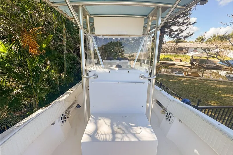 Slide: The Image of 2006 Dusky 278 boat interior with console, surrounded by lush greenery and waterfront view. - 44