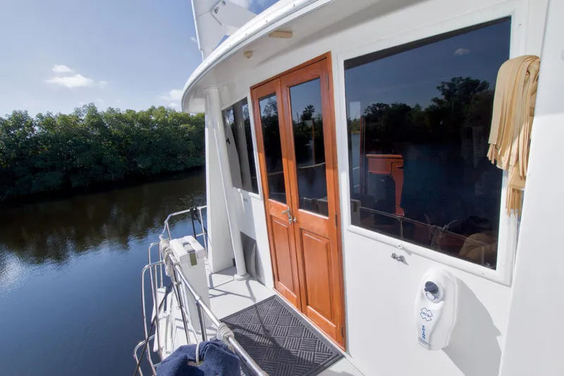 Slide: The Image of 1985 Gulfstar 44 Motor Yacht on calm river, featuring wooden doors and scenic view. - 11