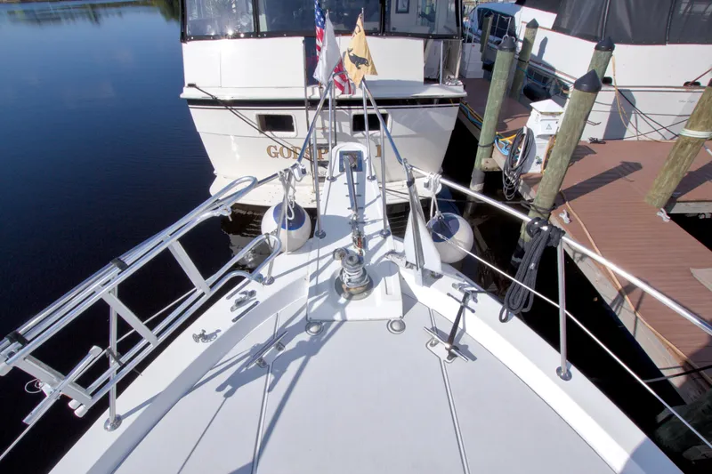 Slide: The Image of 1985 Gulfstar 44 Motor Yacht docked, featuring bow view with railings and flags. - 16