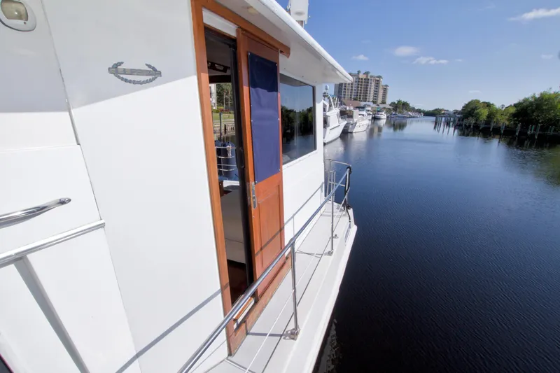 Slide: The Image of 1985 Gulfstar 44 Motor Yacht docked on a serene waterway under a clear blue sky. - 21