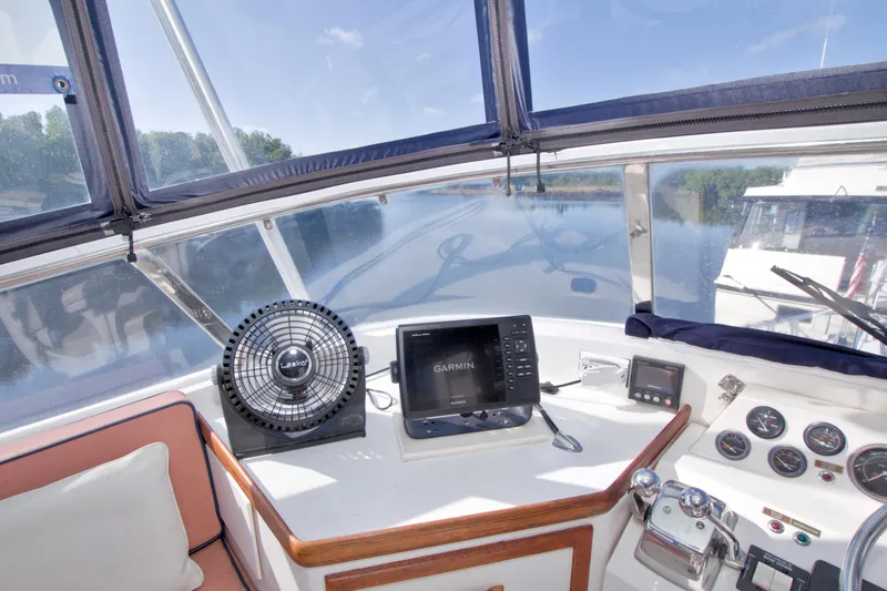 Slide: The Image of 1985 Gulfstar 44 Motor Yacht helm with Garmin navigation and Lasko fan, overlooking serene waters. - 31