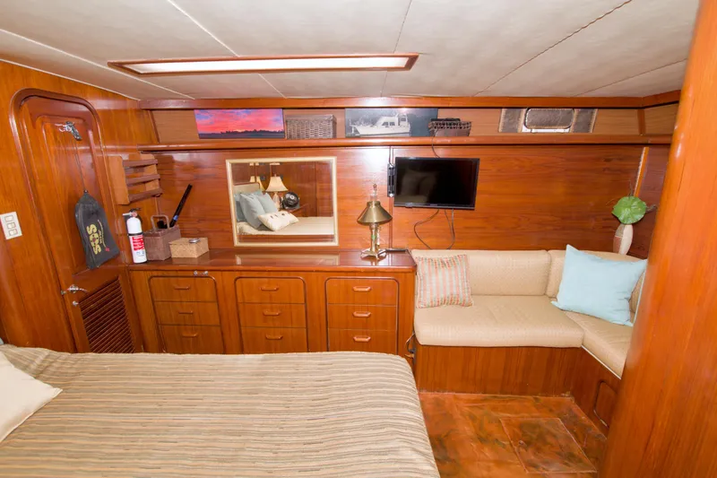 Slide: The Image of 1985 Gulfstar 44 Motor Yacht interior with wood paneling, cozy seating, and a mounted TV. - 59