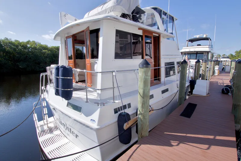 Slide: The Image of 1985 Gulfstar 44 Motor Yacht docked at marina, sunny day, lush greenery in background. - 8
