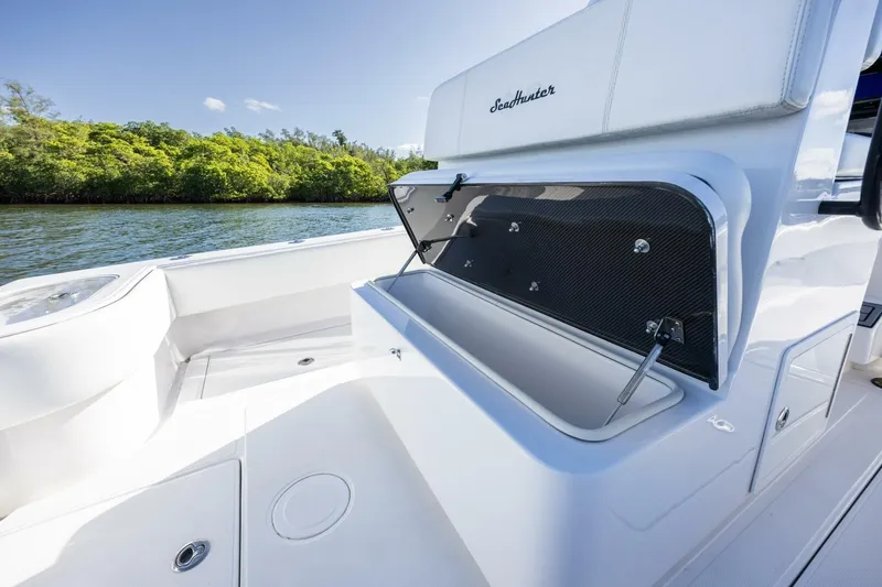 Slide: The Image of 2019 SeaHunter 28 Floridian boat with open storage compartment, near lush shoreline. - 20