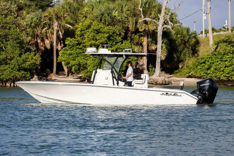 Slide: The Image of 2019 SeaHunter 28 Floridian boat cruising on water near lush greenery. - 25