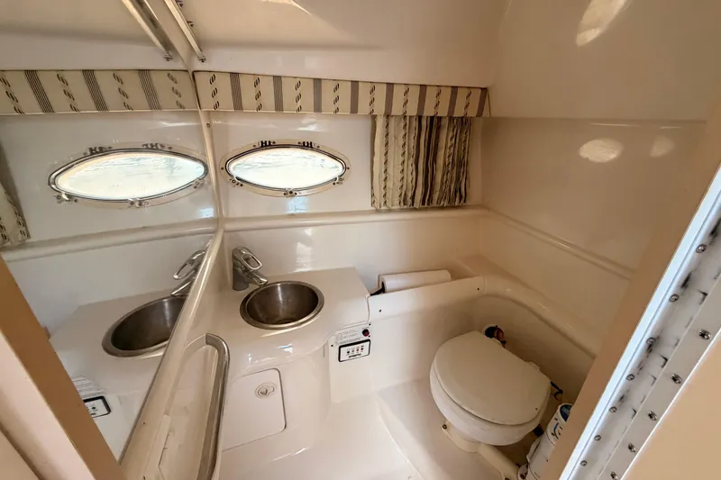 Slide: The Image of 2002 Formula 330 Sun Sport boat bathroom with sink, toilet, and porthole windows. - 46