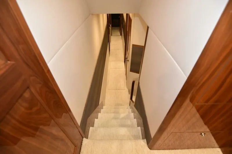 Slide: The Image of Staircase inside 2017 Viking 80 Sky Bridge yacht with wooden paneling and carpeted steps. - 38