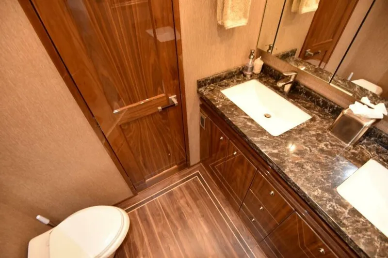 Slide: The Image of Luxurious bathroom in 2017 Viking 80 Sky Bridge yacht with marble countertop and wooden cabinetry. - 48