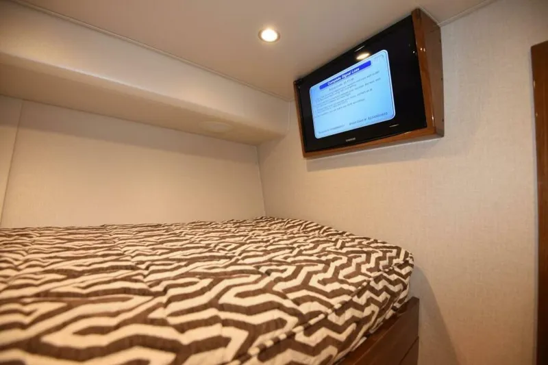 Slide: The Image of 2017 Viking 80 Sky Bridge cabin with patterned bedding and wall-mounted TV. - 60