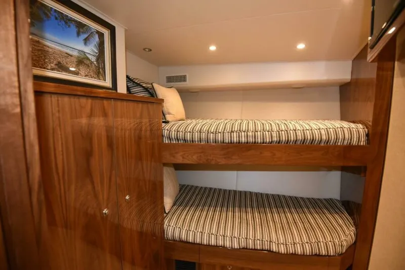 Slide: The Image of Bunk beds in 2017 Viking 80 Sky Bridge yacht cabin with wood finish and beach artwork. - 62