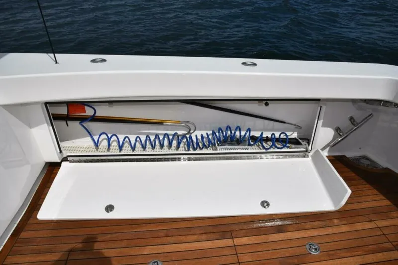 Slide: The Image of Storage compartment on 2017 Viking 80 Sky Bridge yacht with coiled hose and wooden deck. - 96