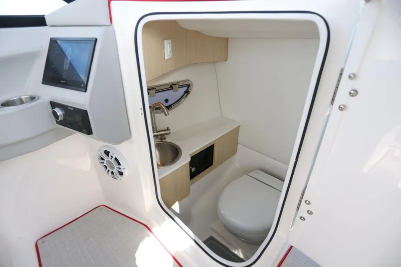 Slide: The Image of Manufacturer Provided Image: 2026 Regal LX6 boat interior with compact bathroom, featuring sink and toilet. - 7
