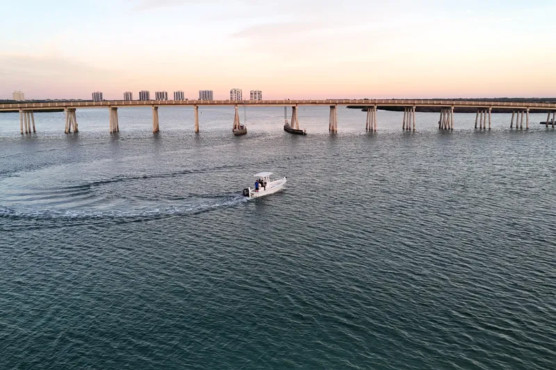 Slide: The Image of A 2016 Dorado 23 boat cruising near a bridge at sunset. - 45