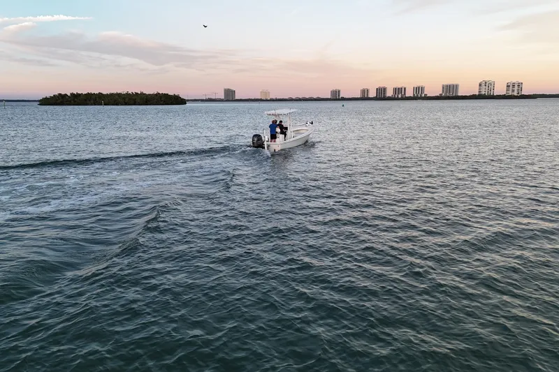 Slide: The Image of Boat cruising on calm water at sunset, city skyline in background. Dorado 23, 2016 model. - 48