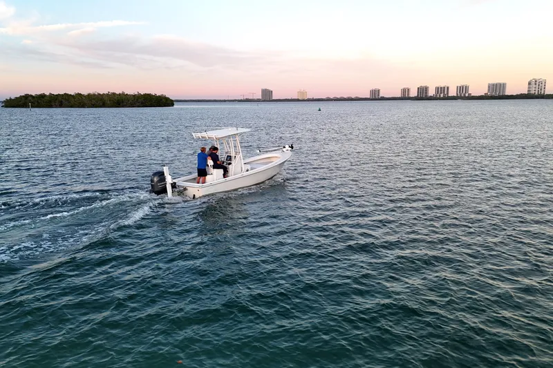 Slide: The Image of 2016 Dorado 23 boat cruising on calm water at sunset, with city skyline in background. - 50