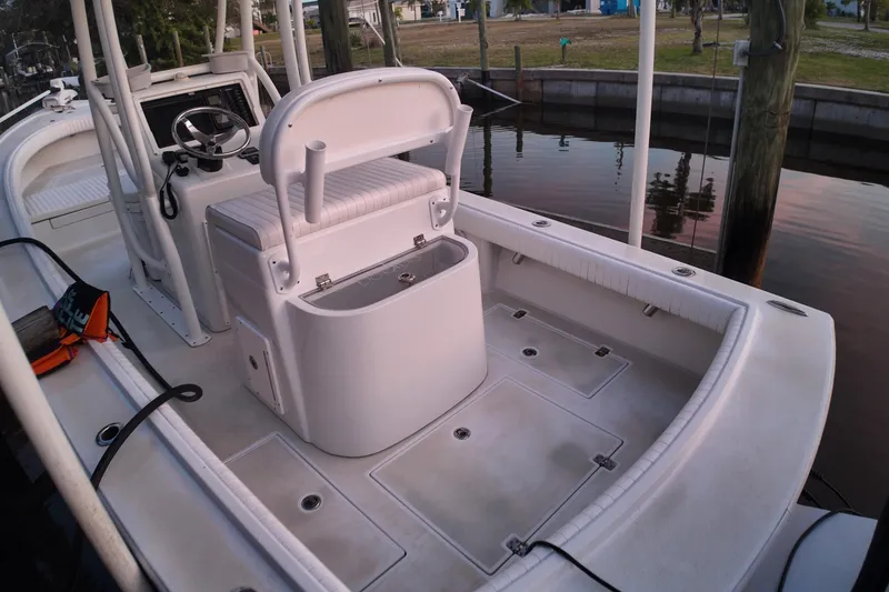 Slide: The Image of 2016 Dorado 23 boat interior with seating and steering console, docked by calm water. - 54