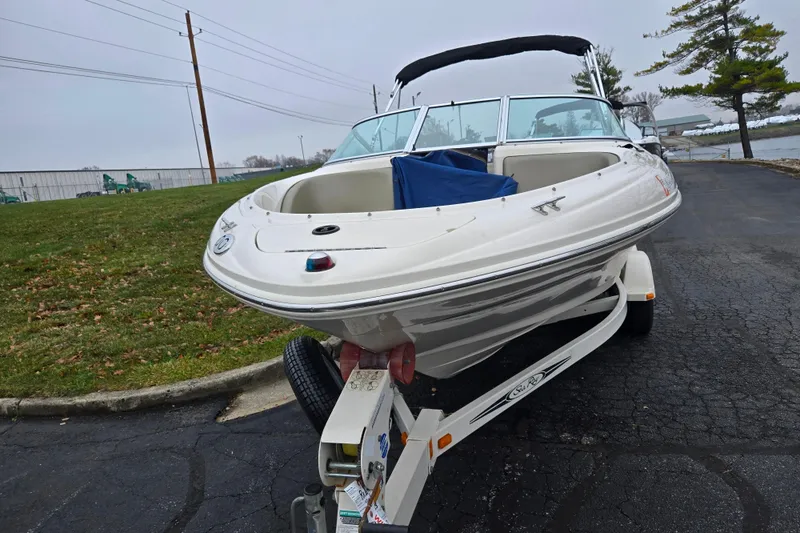 Slide: The Image of 2004 Sea Ray 200 Sport boat on trailer, parked on asphalt near grassy area. - 6