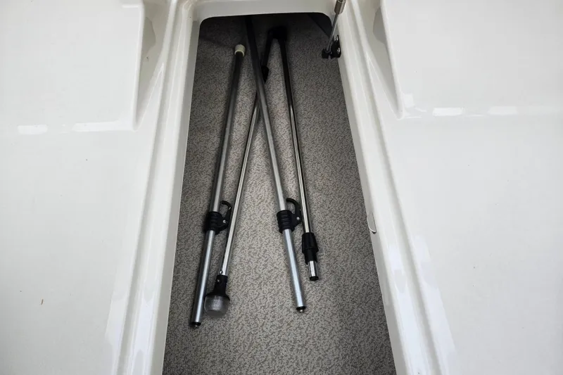 Slide: The Image of Storage compartment with metal poles in a 2016 Stingray 198 RX boat. - 15